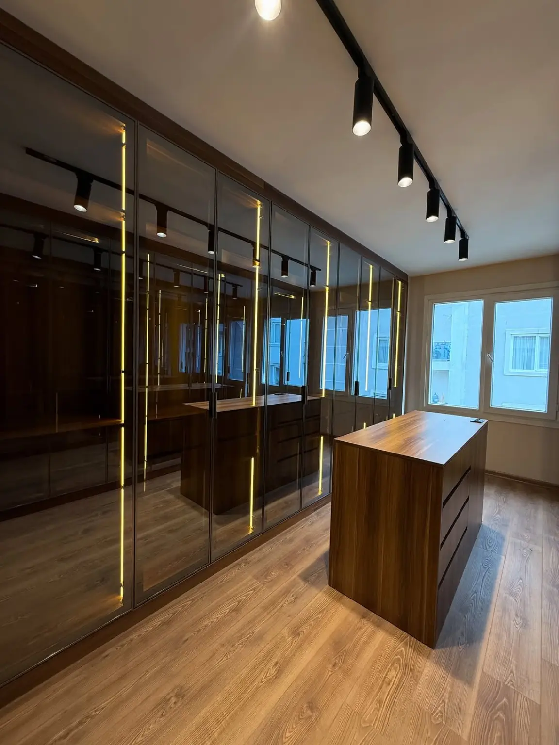 Vestidor de cristal ahumado con isla e iluminación LED de BNZ Mueble